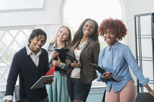 Young professionals holding laptops and smiling